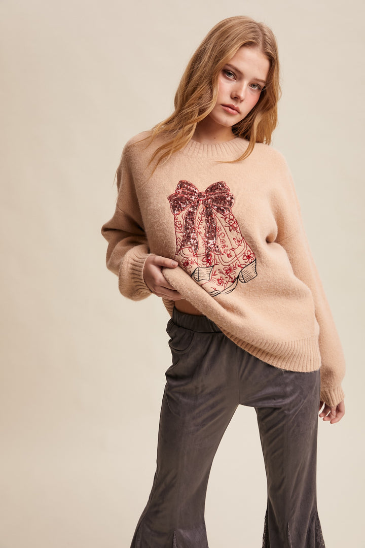 Woman wearing a beige sweater with a floral design and gray pants on a beige background