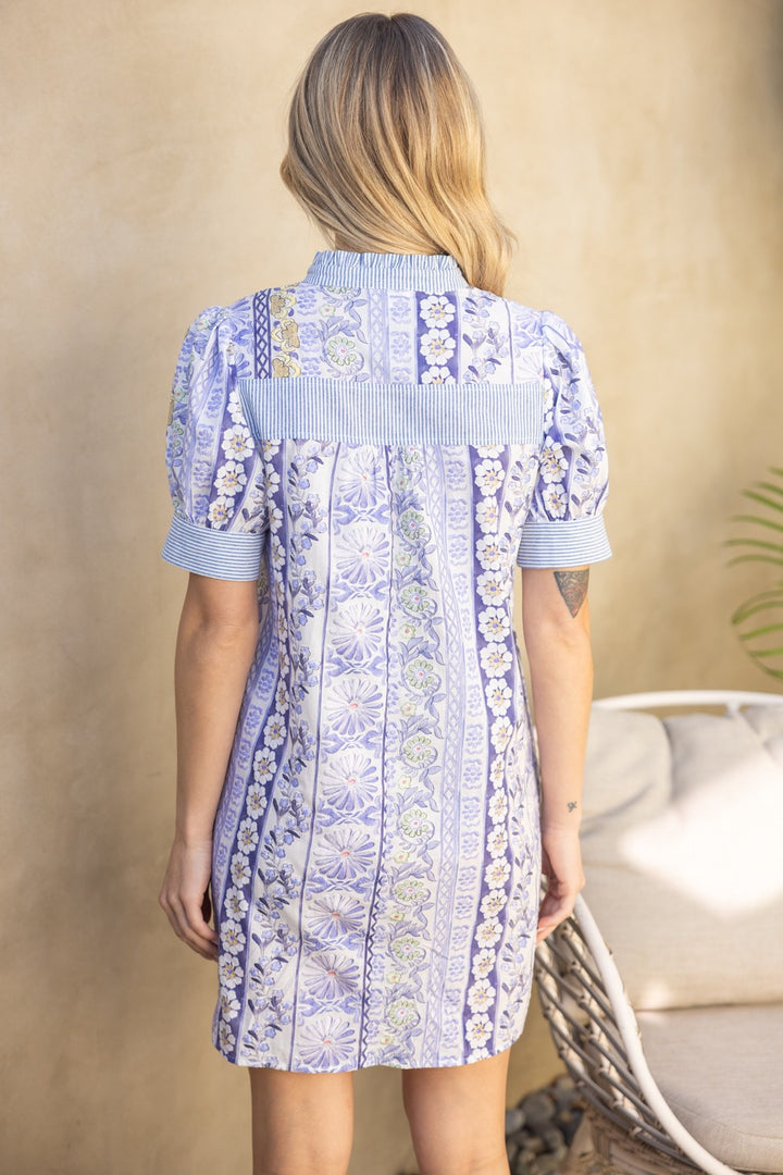 Woman wearing a blue floral dress against a beige background