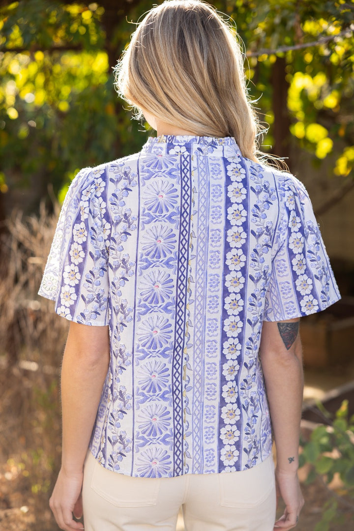 Woman wearing a blue patterned shirt with a blurred natural background