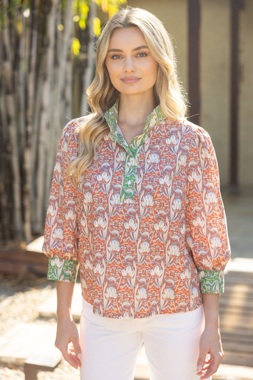 Woman wearing a patterned blouse with a blurred natural background