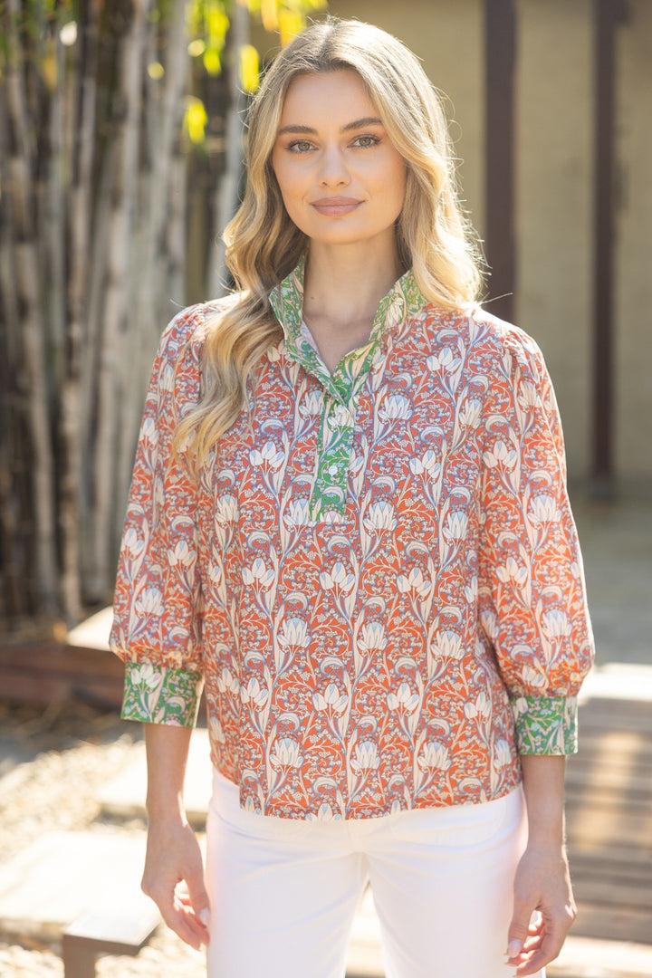 Woman wearing a patterned blouse with a blurred natural background