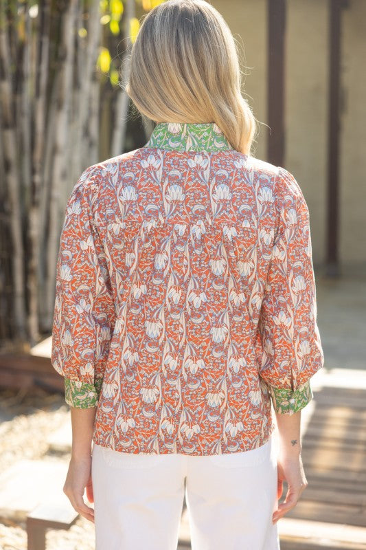 Woman wearing a patterned blouse with a blurred outdoor background