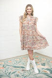 Woman wearing a floral dress standing on a patterned rug with a white wall background