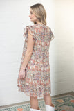Woman wearing a floral dress against a white wall.
