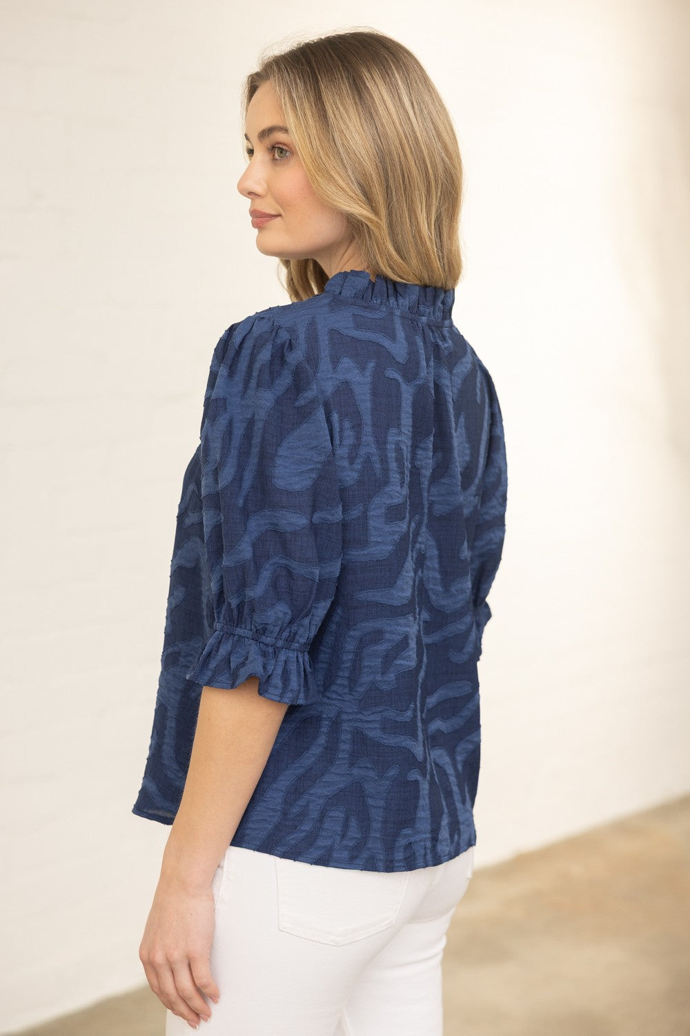 Woman wearing a blue patterned blouse against a plain background