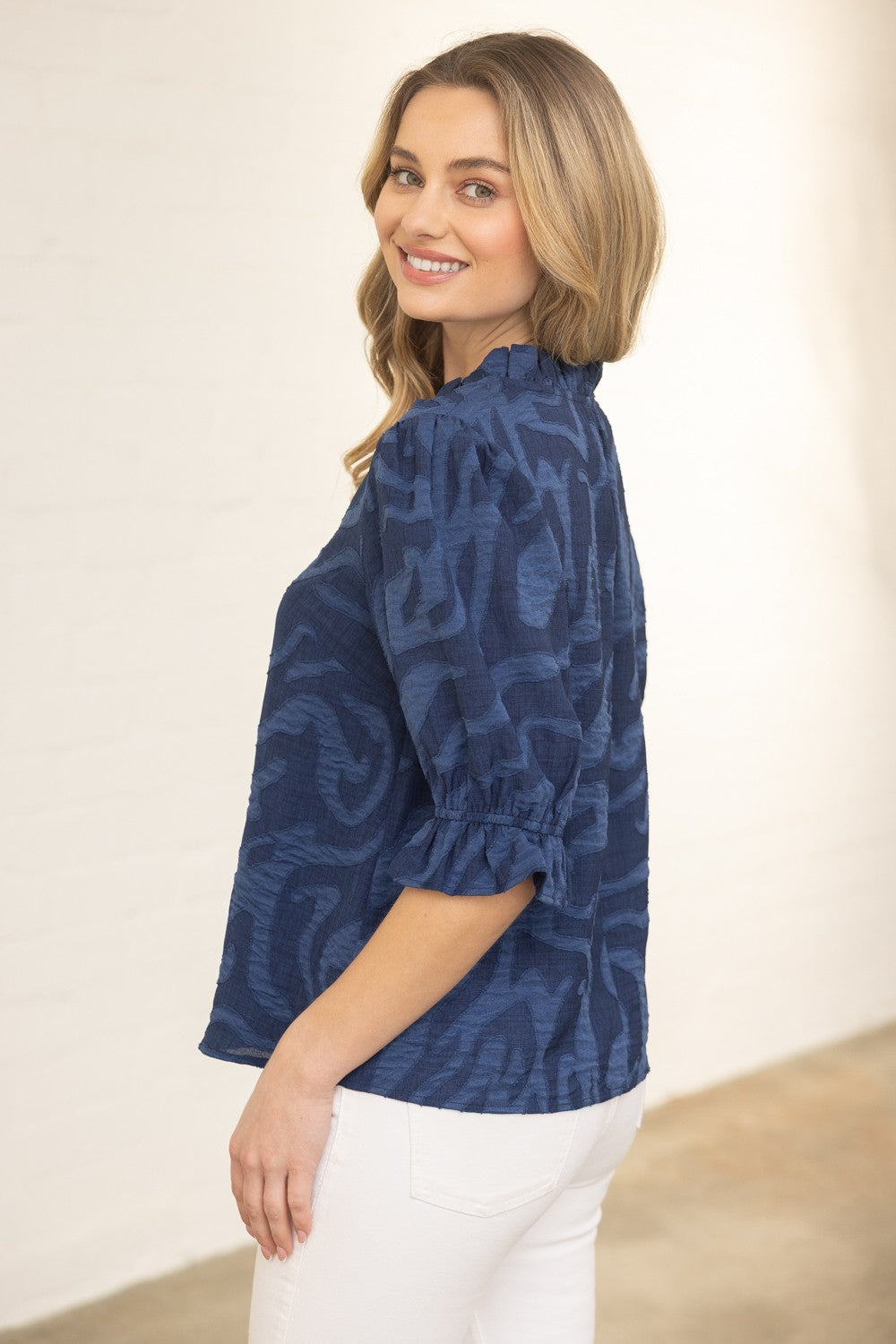 Woman wearing a blue patterned blouse against a plain background