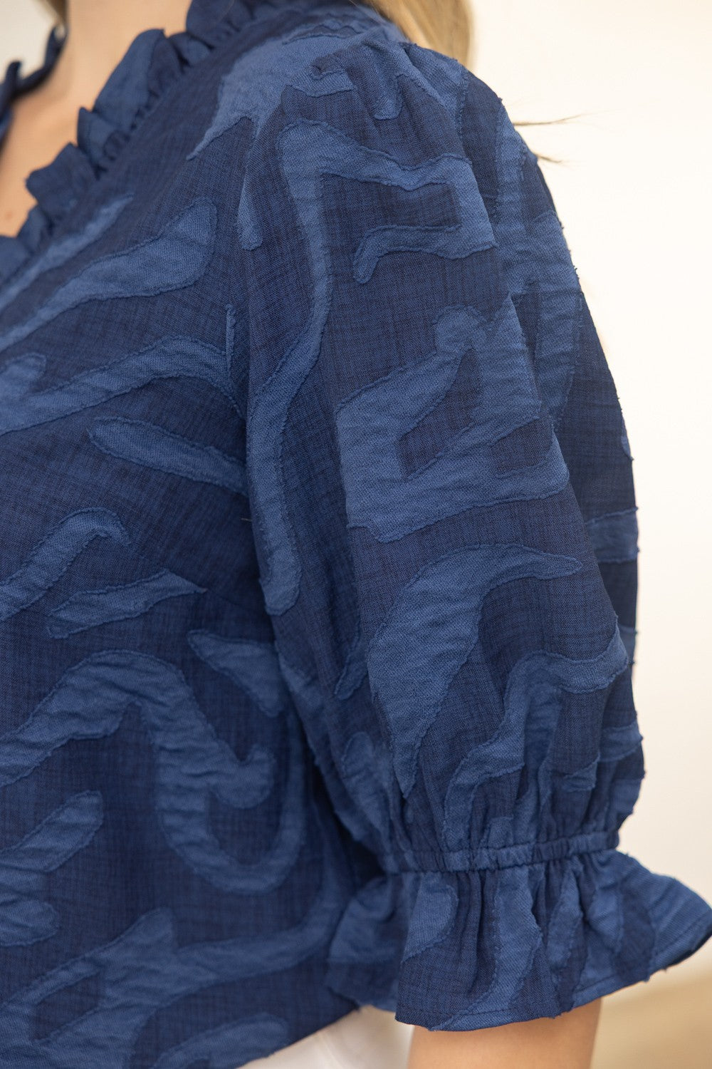 Close-up of a blue patterned blouse with ruffled sleeves on a plain background