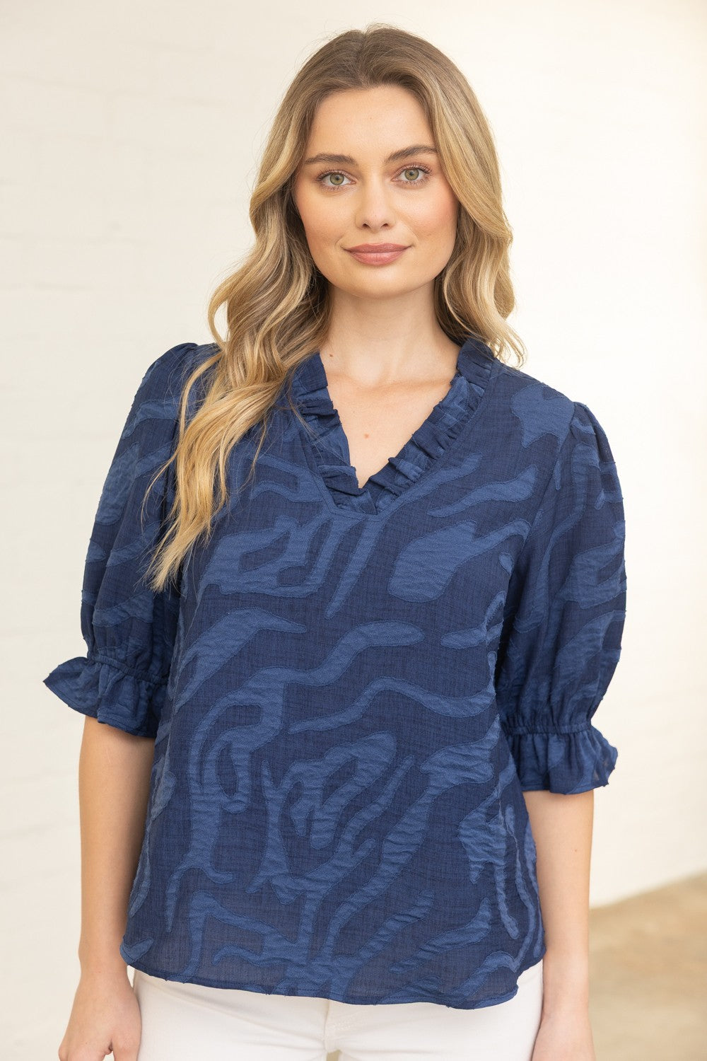 Woman wearing a blue patterned blouse against a beige background