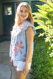 Woman wearing a floral top standing outdoors with greenery in the background