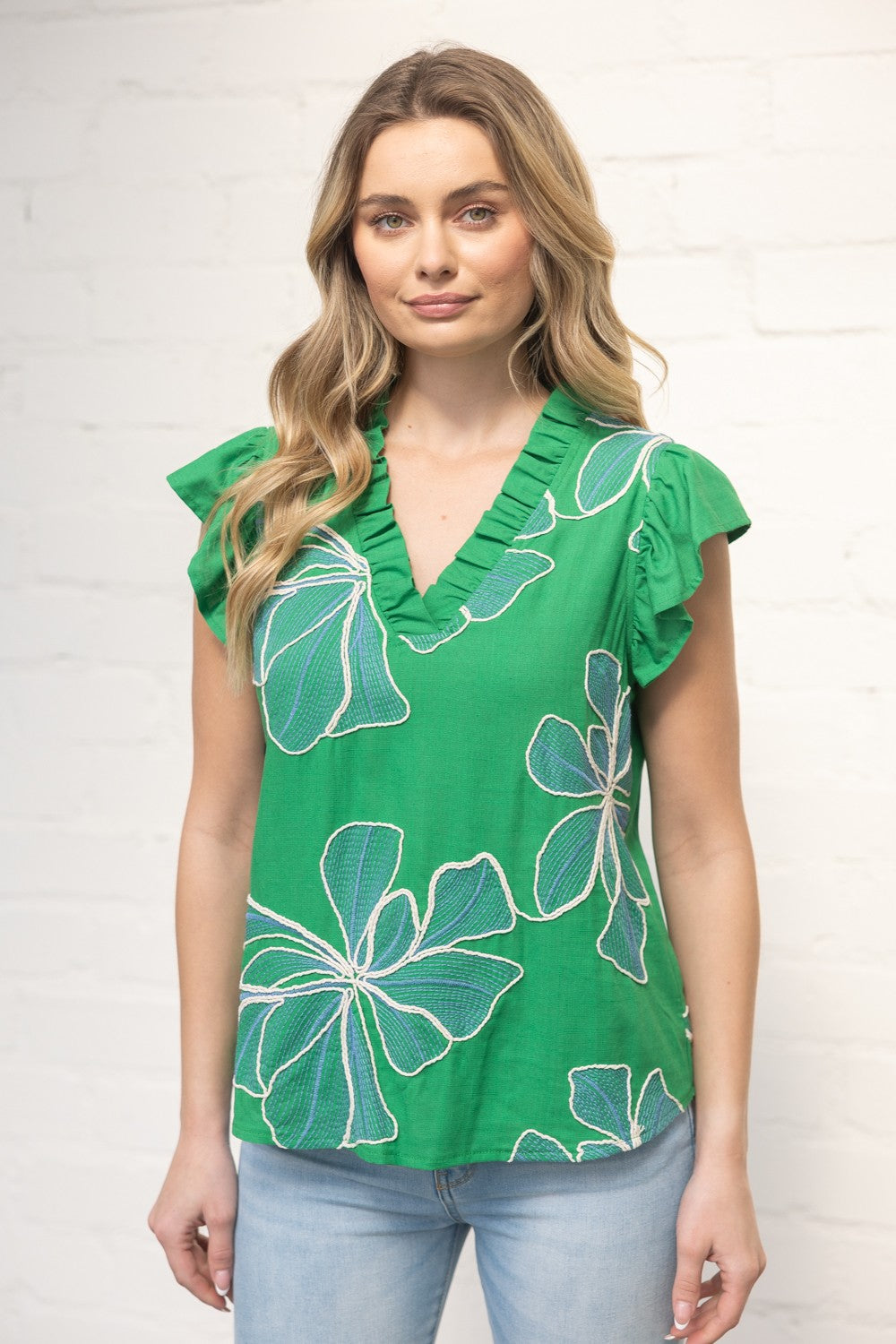 Woman wearing a green floral top against a white background