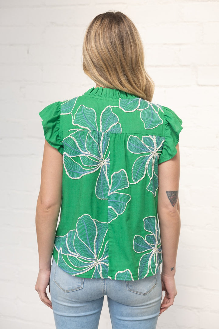 Woman wearing a green floral top against a white background