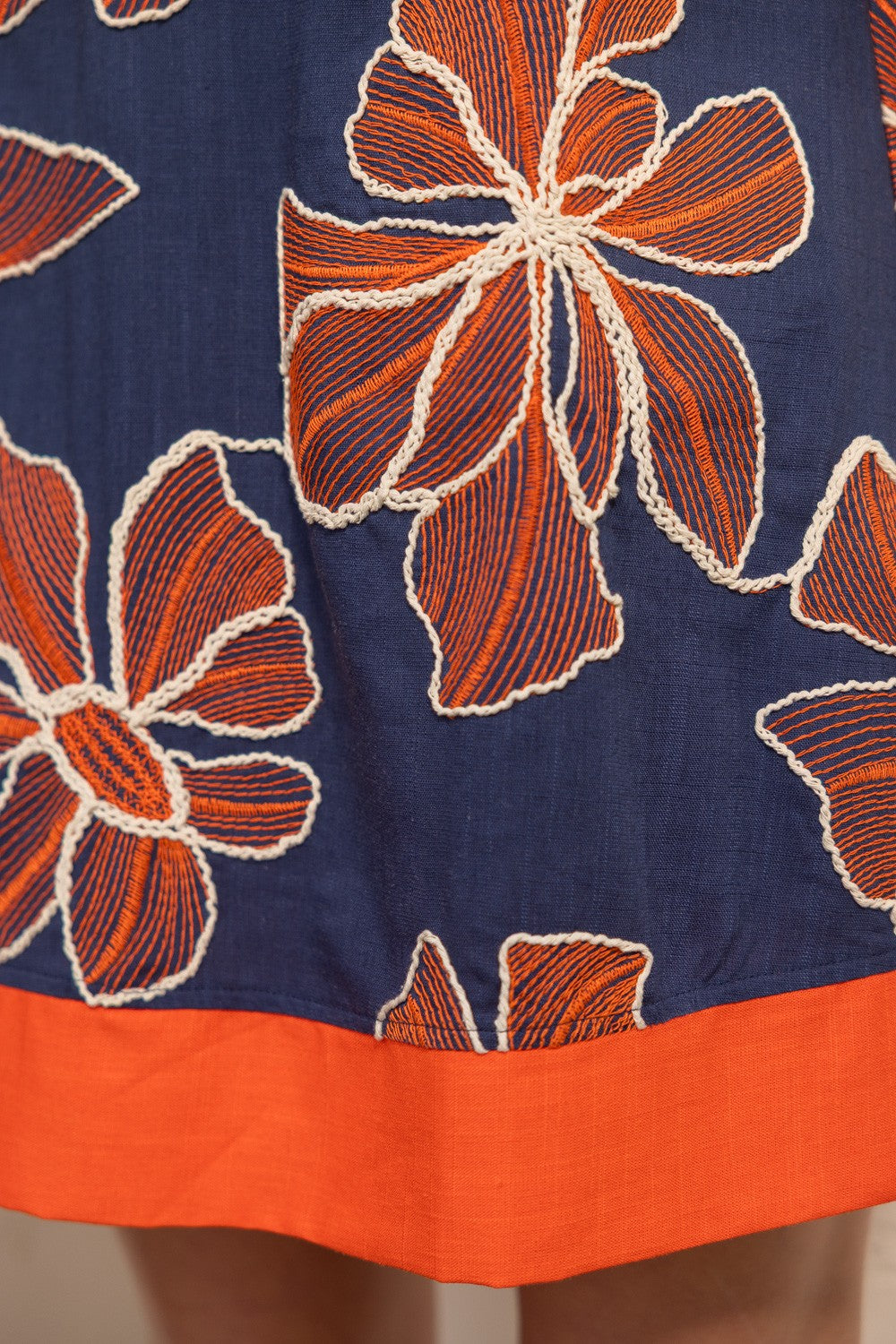 Woman wearing a navy dress with orange floral pattern indoors