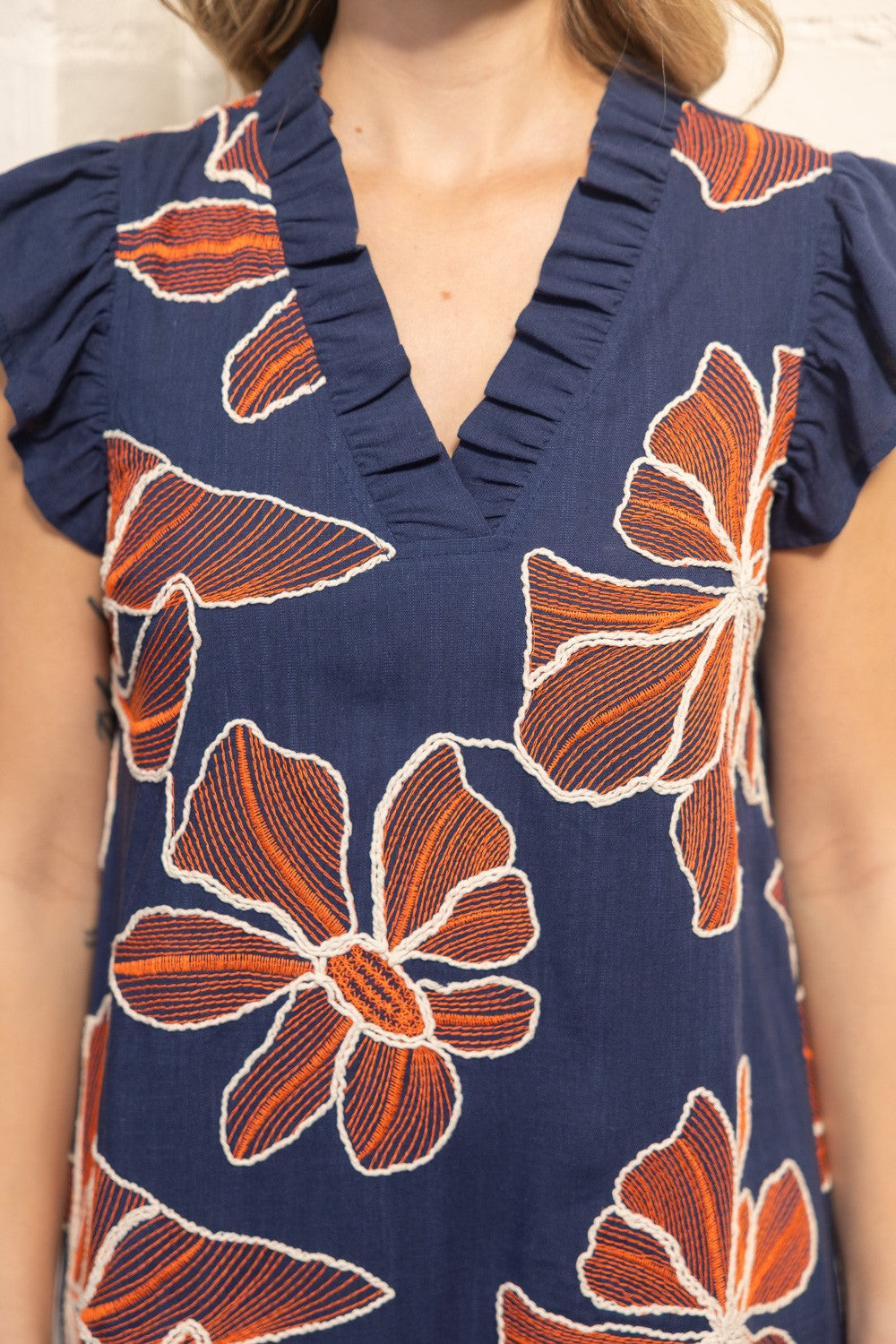 Woman wearing a navy dress with orange floral pattern indoors
