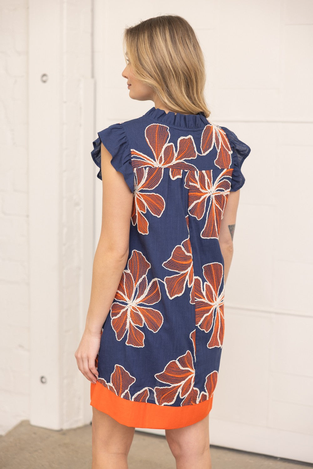 Woman wearing a navy dress with orange floral pattern indoors