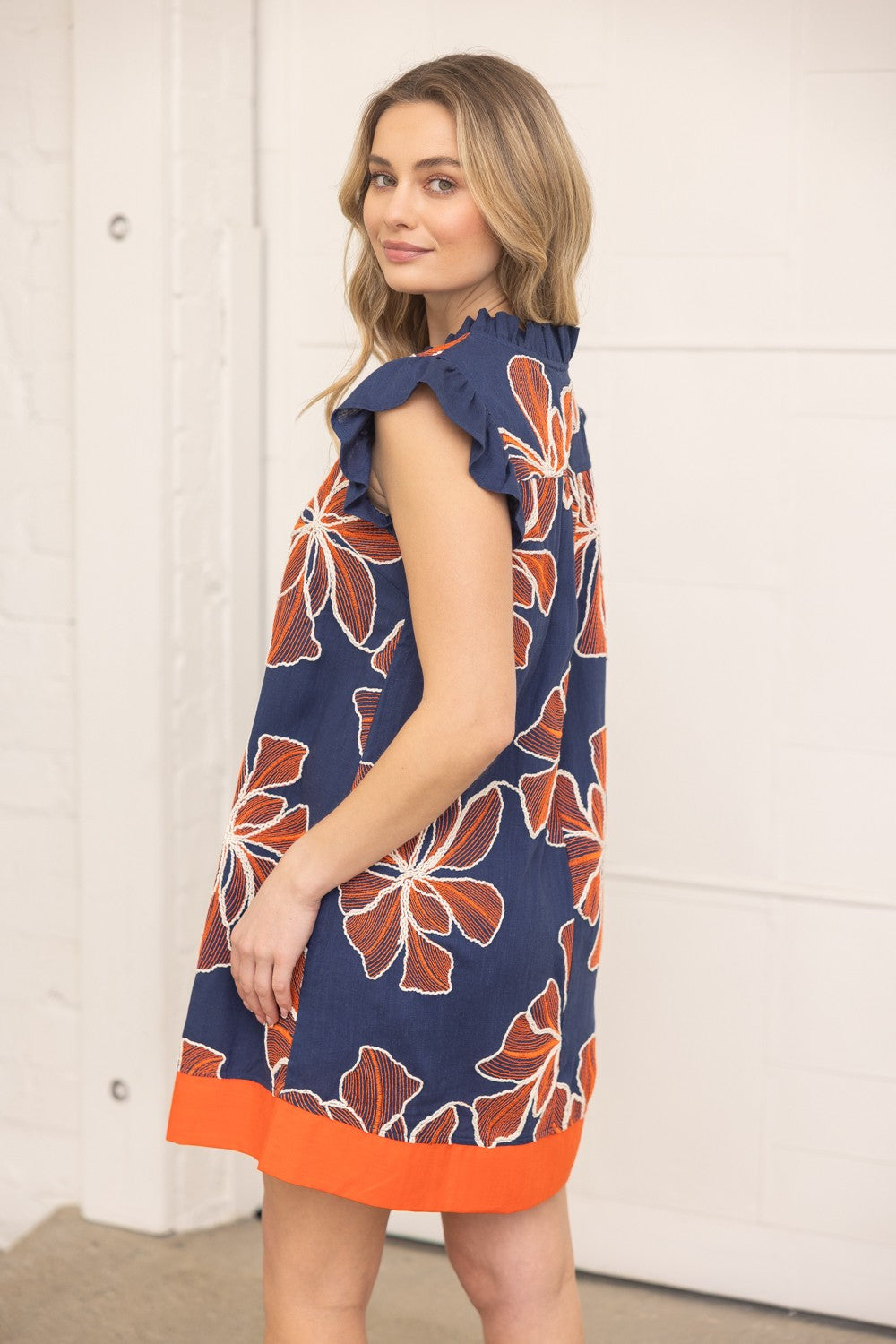 Woman wearing a navy dress with orange floral pattern indoors