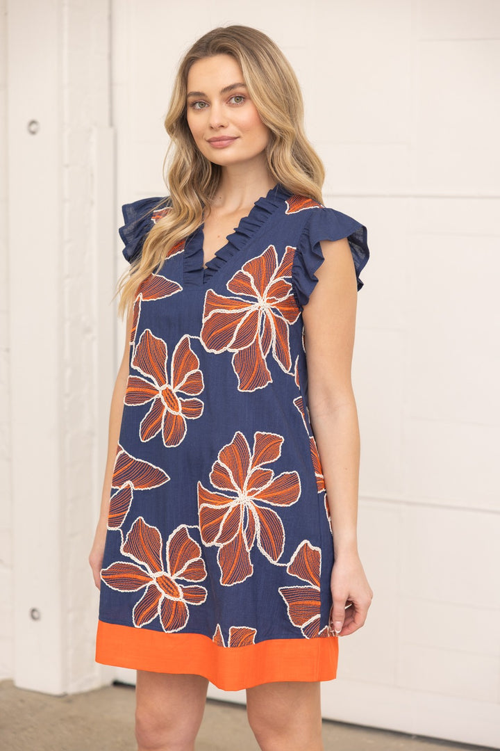Woman wearing a navy dress with orange floral pattern indoors
