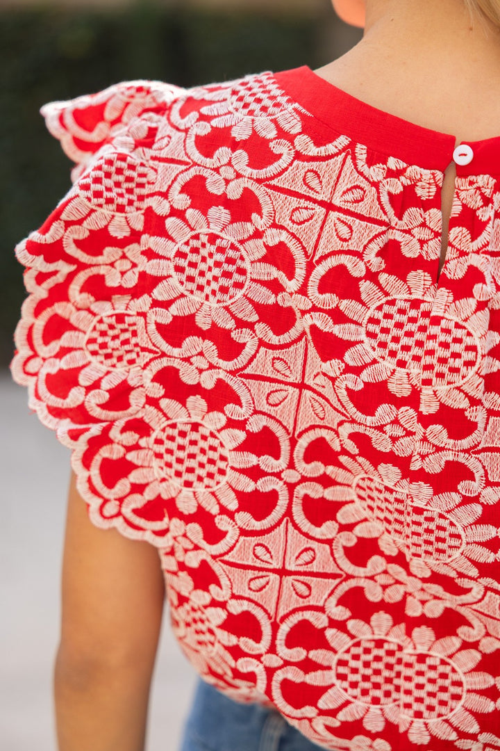 Red garment with white intricate lace detailing on a blurred background