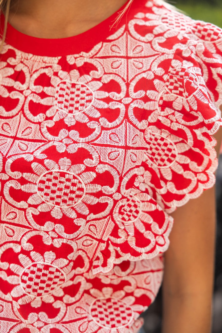 Close-up of a red and white lace garment with intricate patterns.