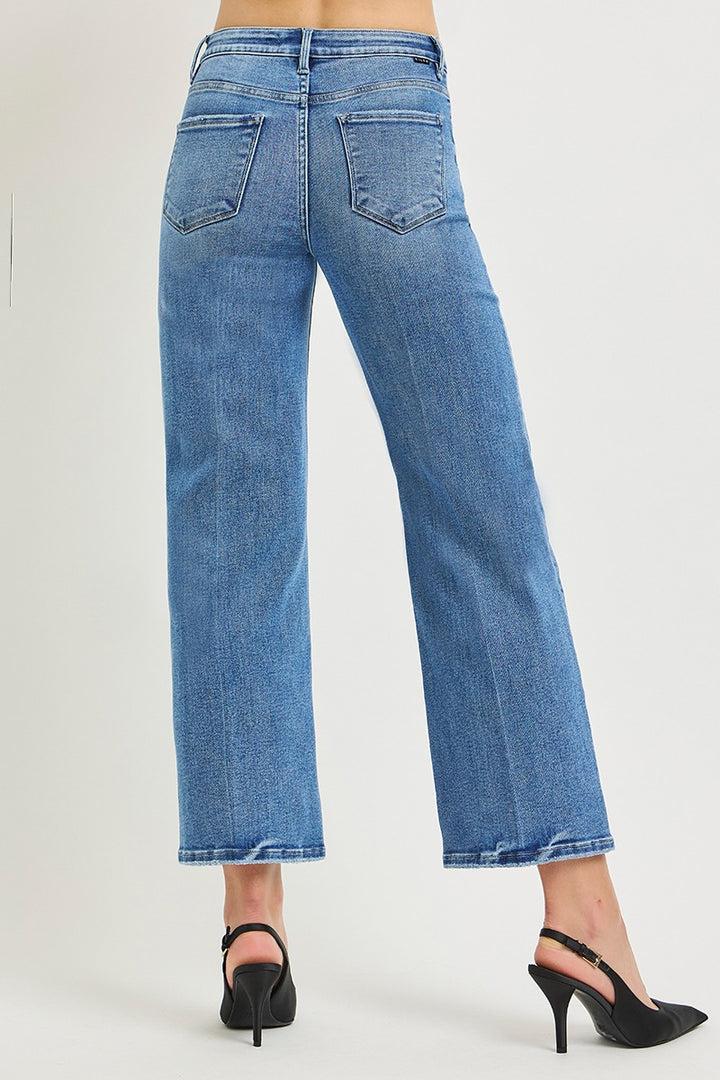 Blue jeans worn by a person on a plain background