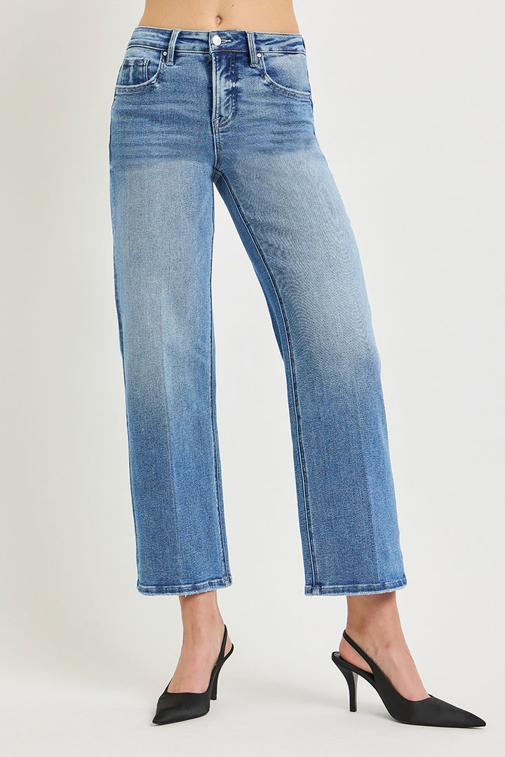 A model from the waist down wearing light blue cropped jeans with a straight-to-wide leg, paired with black slingback high heels, against a light gray studio background.