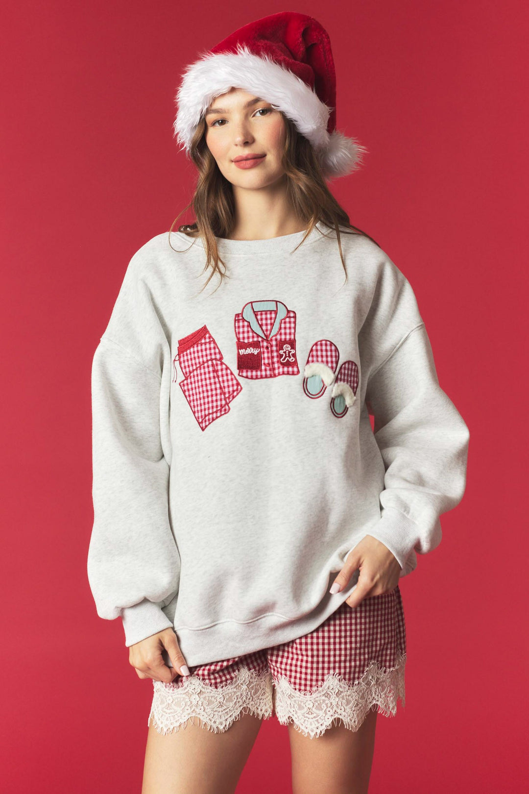 A woman modeling a light gray crewneck sweatshirt with a red and white gingham &