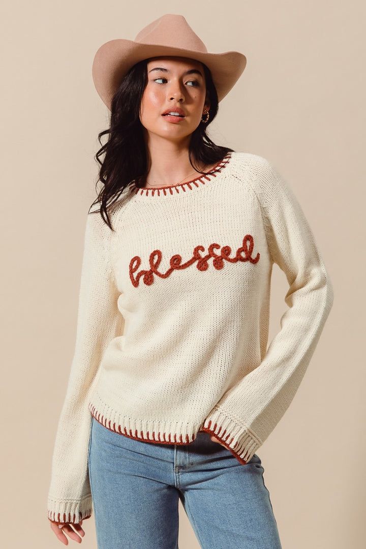 Woman wearing a cream sweater with &