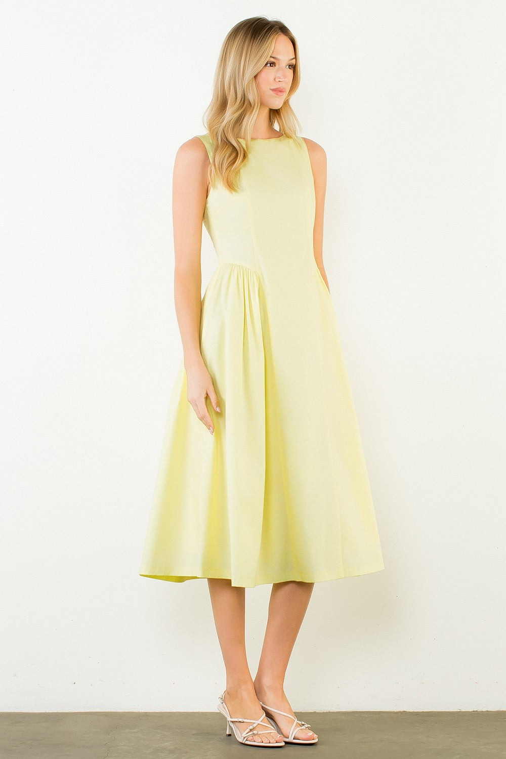 Woman wearing a light yellow dress against a white background