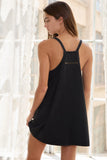 Woman wearing a black slip dress with thin straps in a softly lit room.