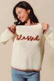 Woman wearing a cream sweater with 'blessed' in red text on a beige background