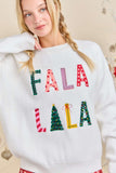Woman wearing a white sweater with colorful text and Christmas-themed designs.