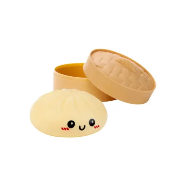 Plush toy resembling a dumpling with a smiling face next to an open tan container on a white background