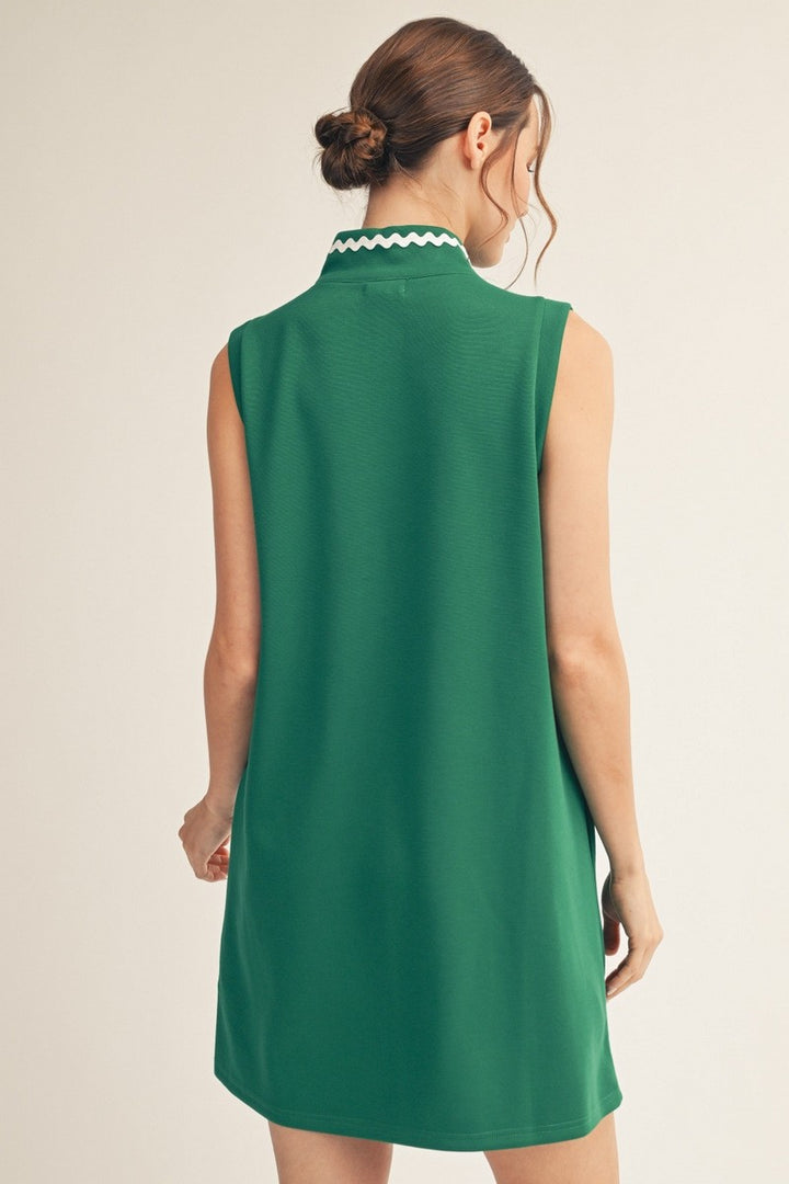 Green sleeveless dress with white trim on a beige background