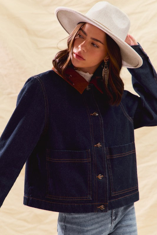 Woman wearing a navy jacket with a red collar and white hat on a beige background