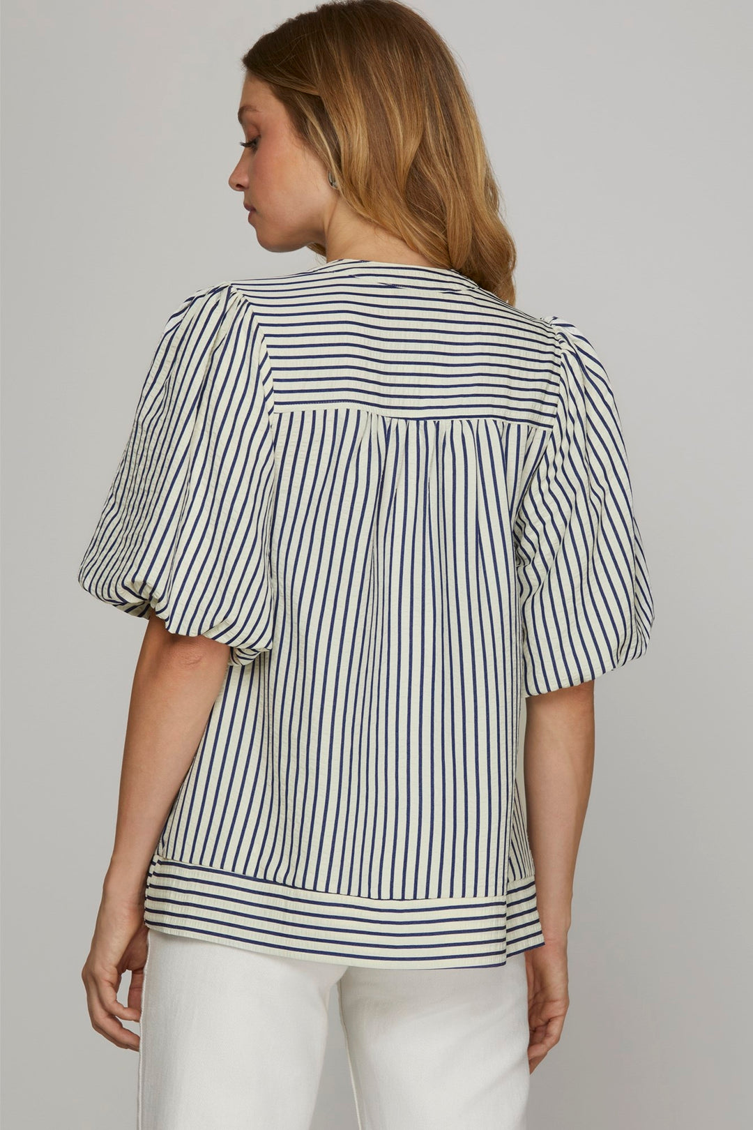 Woman wearing a striped blouse with puffed sleeves against a plain background