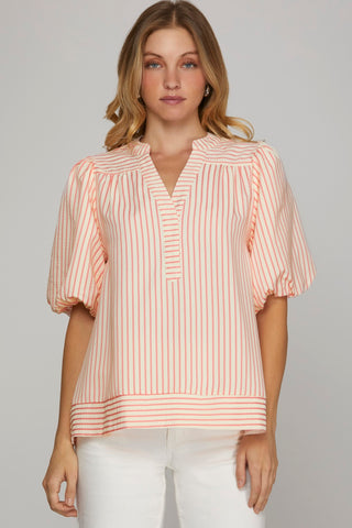 Woman wearing a pink and white striped blouse against a gray background