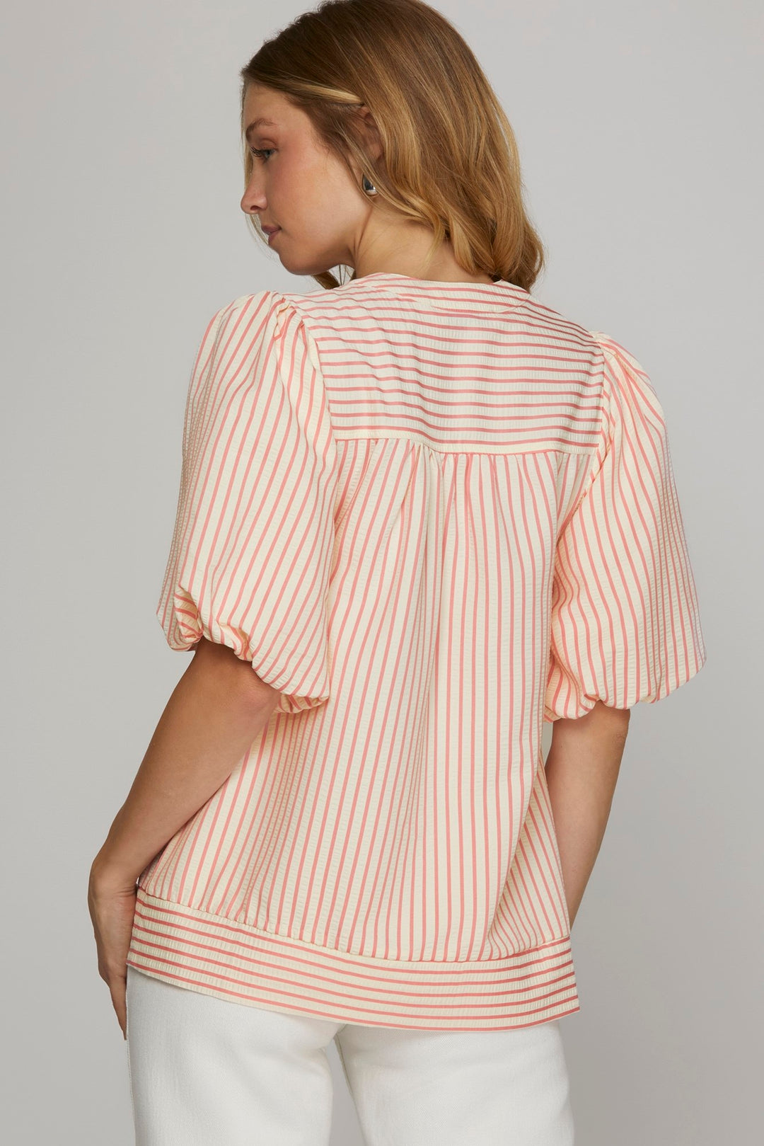 Woman wearing a pink and white striped blouse against a plain background