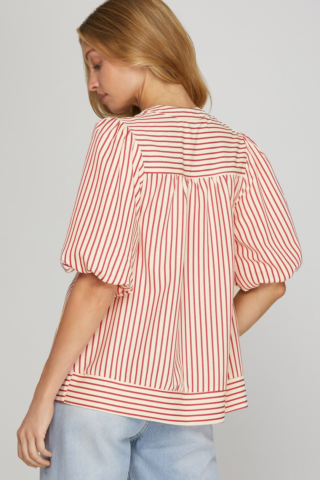 Woman wearing a red and white striped blouse with puffed sleeves on a gray background