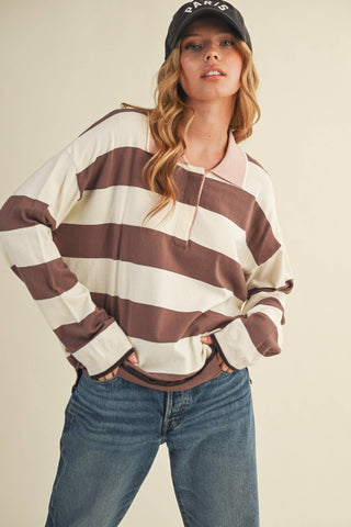 Woman wearing a striped sweater and cap against a plain background
