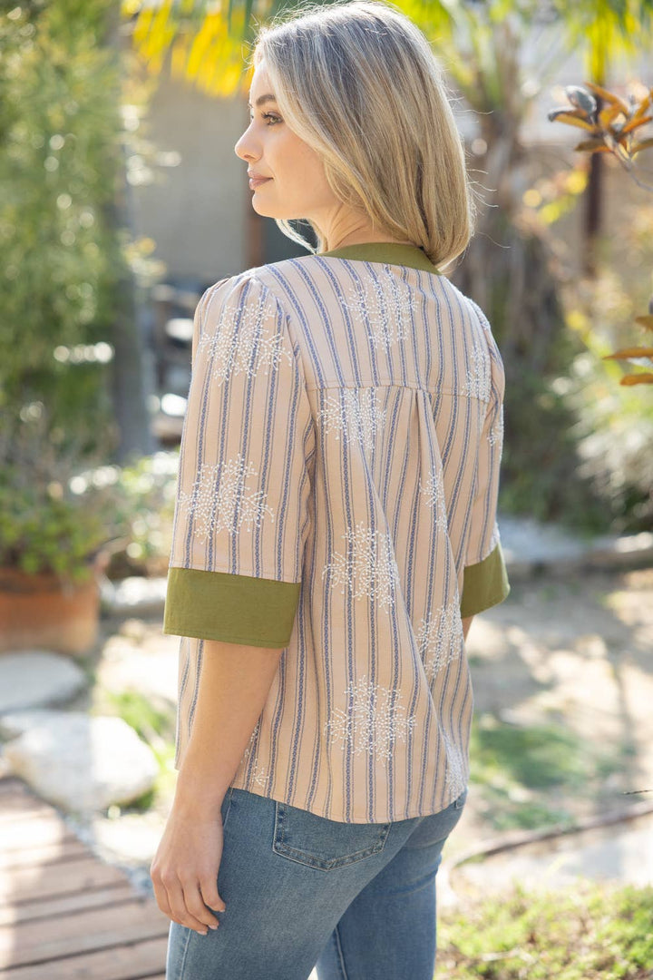 Woman wearing a striped shirt with floral embroidery in an outdoor setting