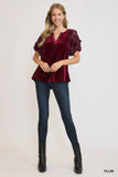 Woman wearing a burgundy velvet top with ruffled sleeves on a white background
