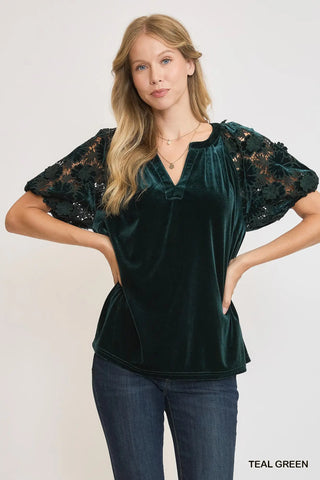 Woman wearing a teal green blouse with lace sleeves on a white background