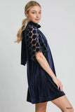 Woman wearing a navy velvet dress with lace details on a white background