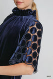 Navy blue velvet garment with intricate lace detailing on sleeves against a neutral background