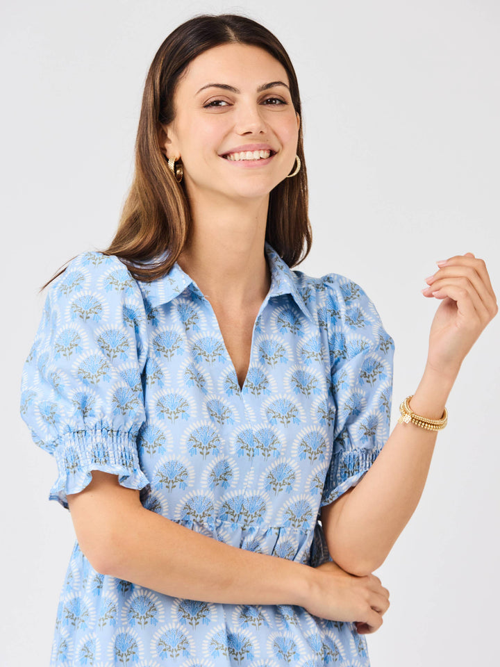 Woman wearing a blue patterned dress against a plain background