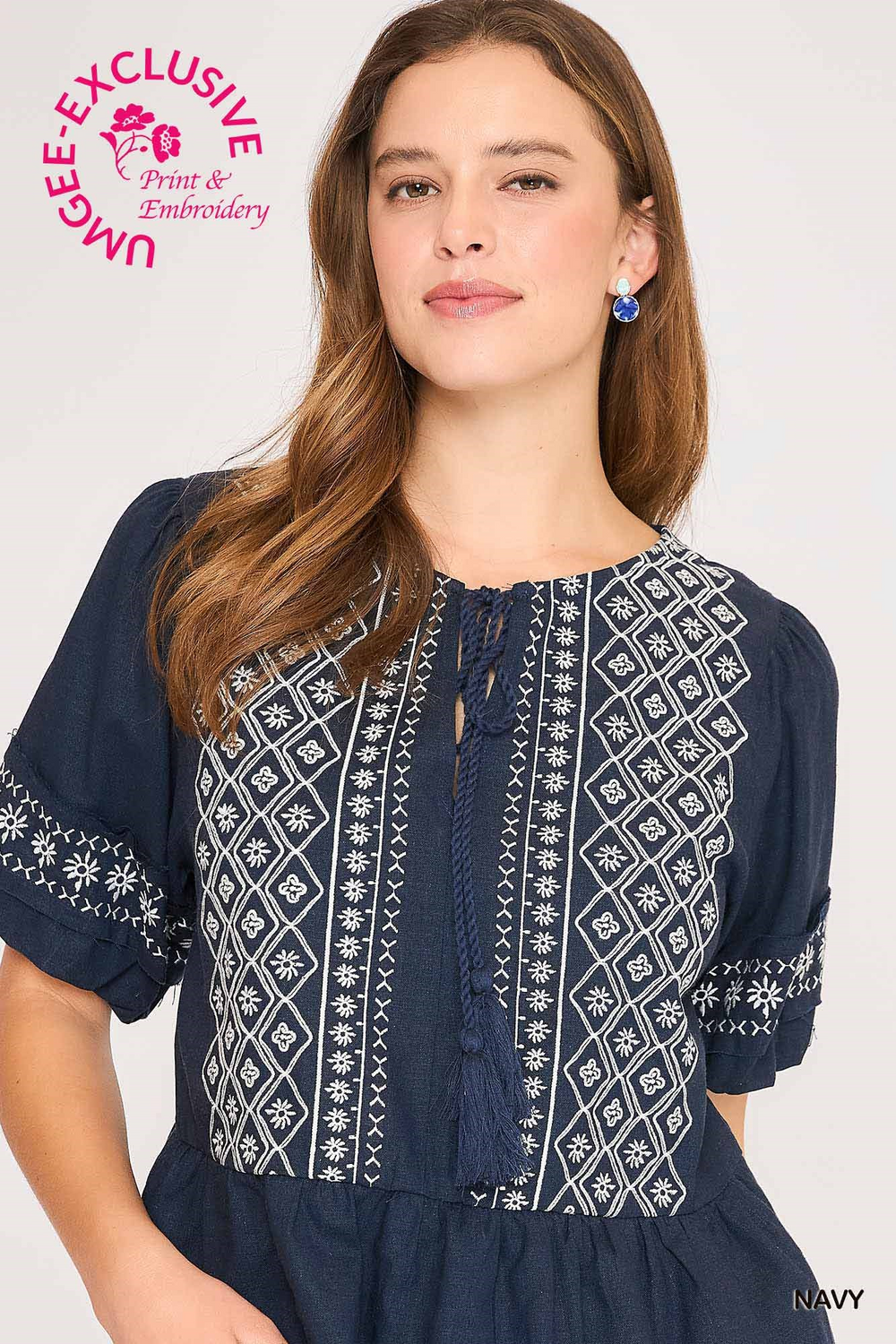 Woman wearing a navy blue dress with white embroidery on a white background, featuring Umgee Exclusive branding.