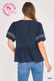 Navy blue top with white embroidery on sleeves worn by a model, against a white background.