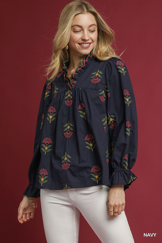 Woman wearing a navy blouse with floral embroidery against a red background
