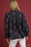 Navy blouse with floral embroidery worn by a person on a red background
