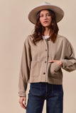 Woman wearing a beige jacket and hat against a beige background
