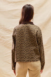 Person wearing a leopard print jacket against a beige background